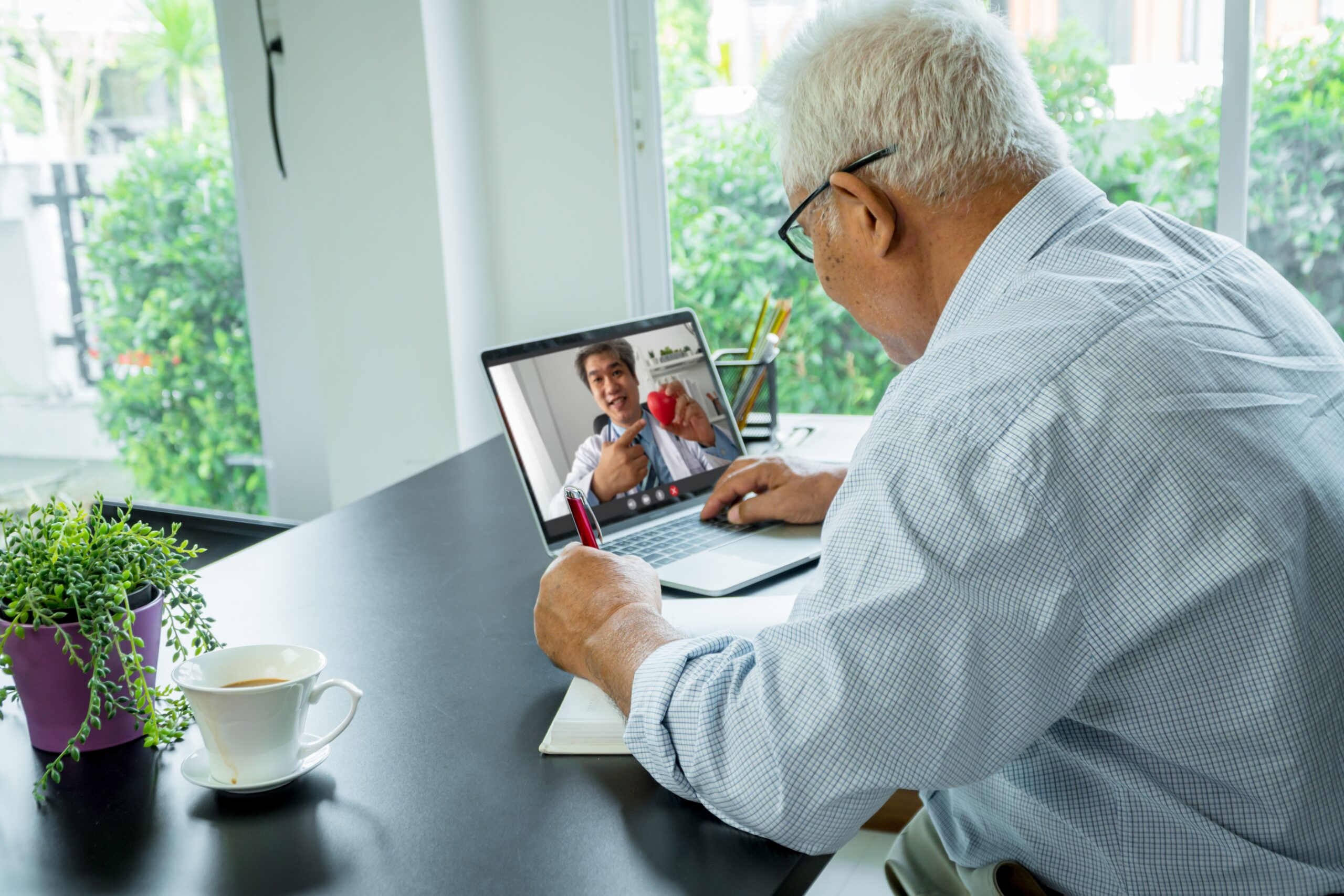 Older man using a laptop for a telemedicine video call with a doctor