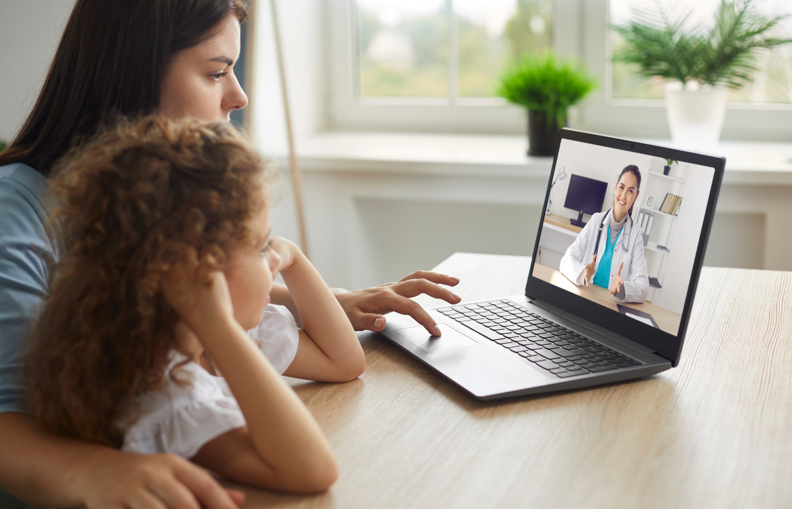 Mother and child speaking with a doctor on a laptop video call